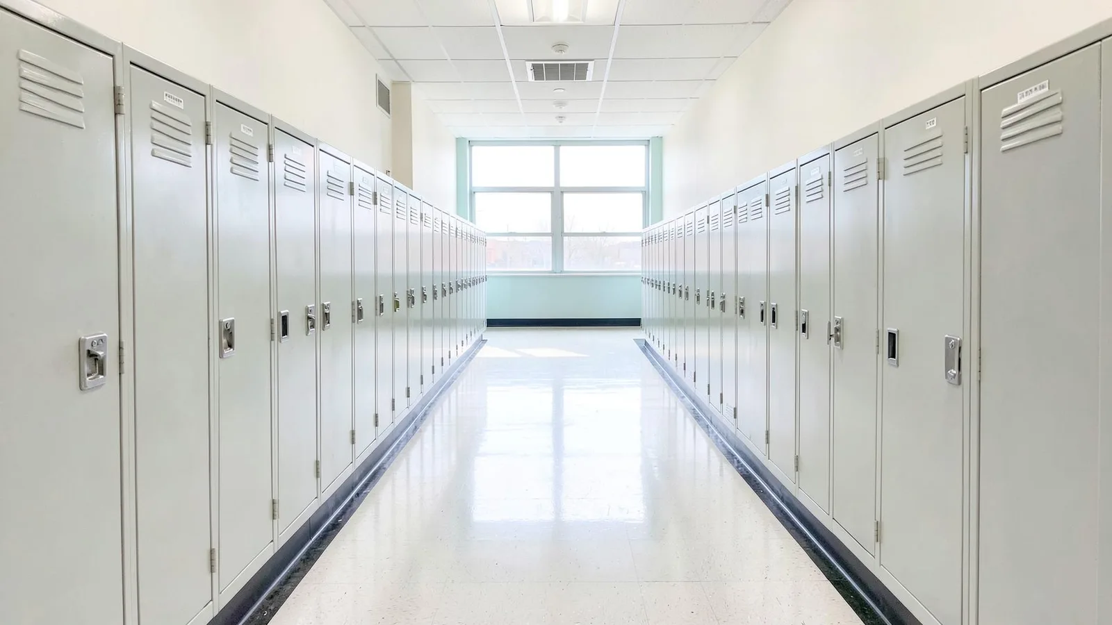 Un couloir de lycée vide et lumineux, avec des casiers alignés en perspective